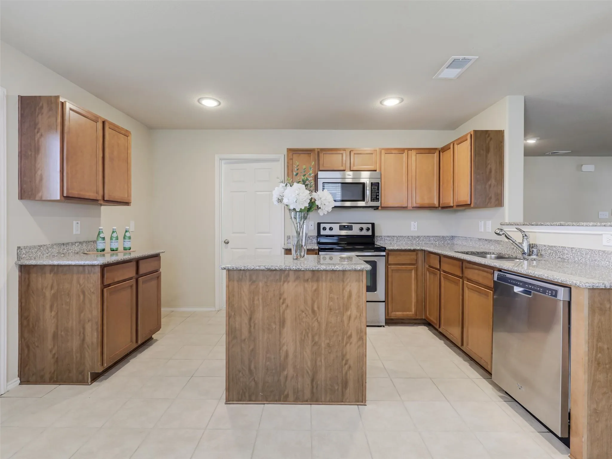Kitchen featuring a central island, light-toned cabinetry, stone countertops, stainless steel appliances, and recessed lighting