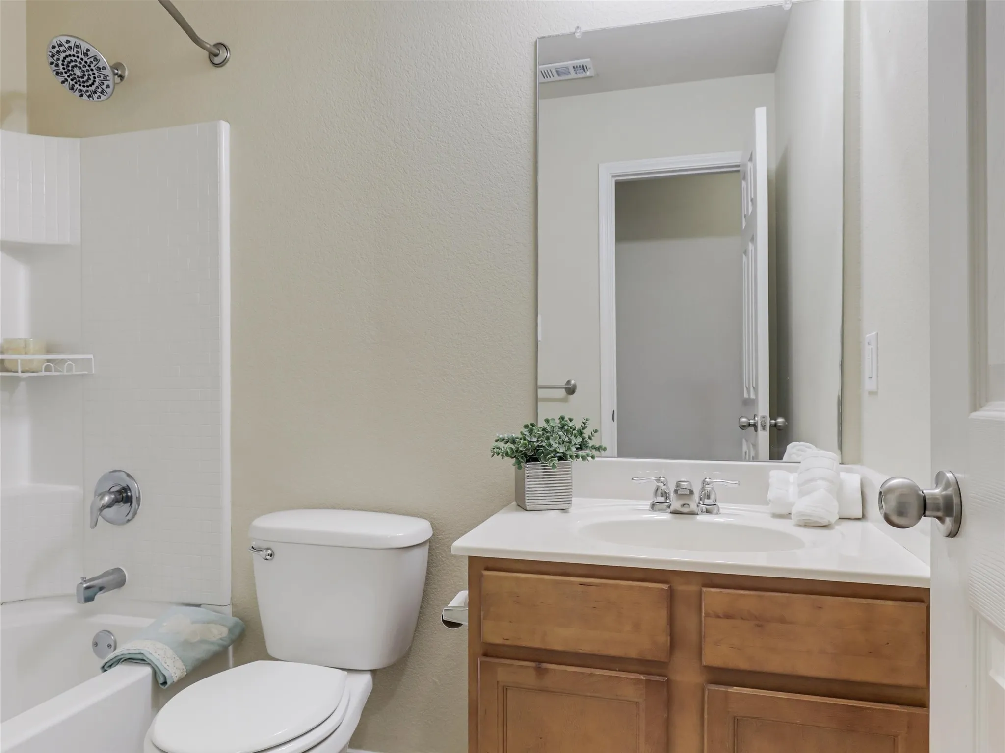 Bathroom featuring a built-in tub with a shower fixture, a vanity with a white countertop, and a wood-finish cabinet