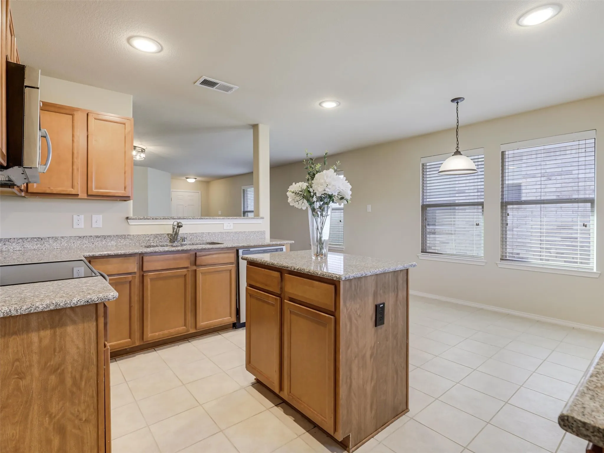 Kitchen featuring wood cabinetry, stone countertops, a central island, recessed lighting, and tile​​‌​​​​‌​​‌‌​‌‌​​​‌‌​‌​‌​‌​​​‌​​ flooring