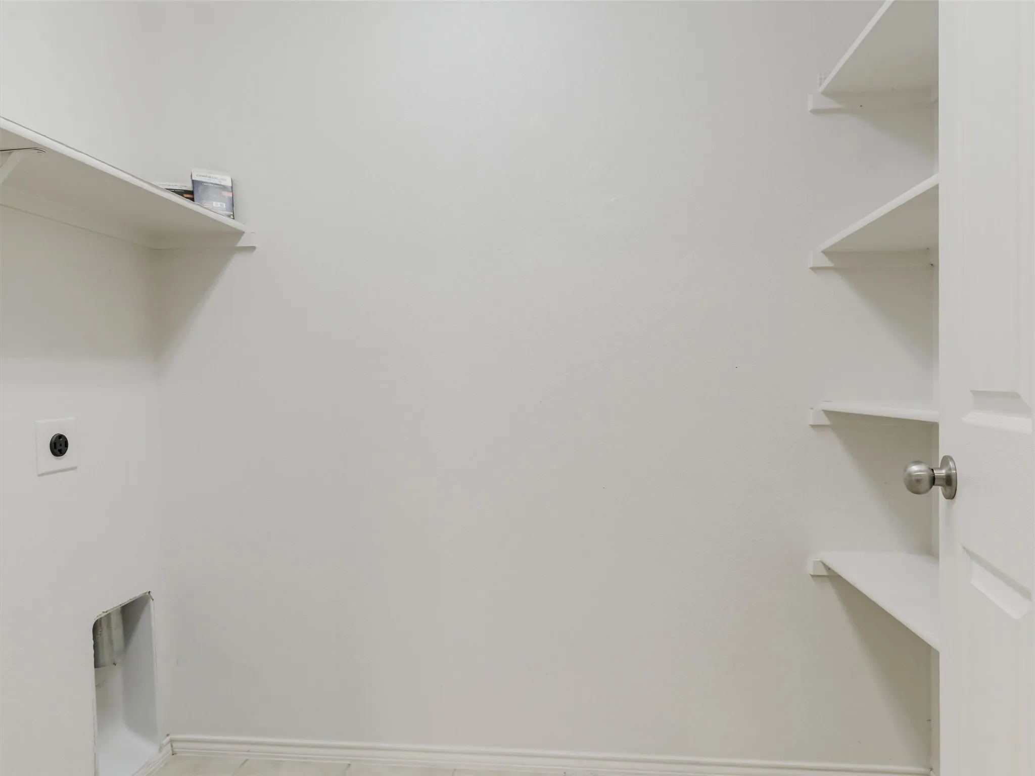Built-in shelving, white door with brushed nickel hardware, and tile flooring