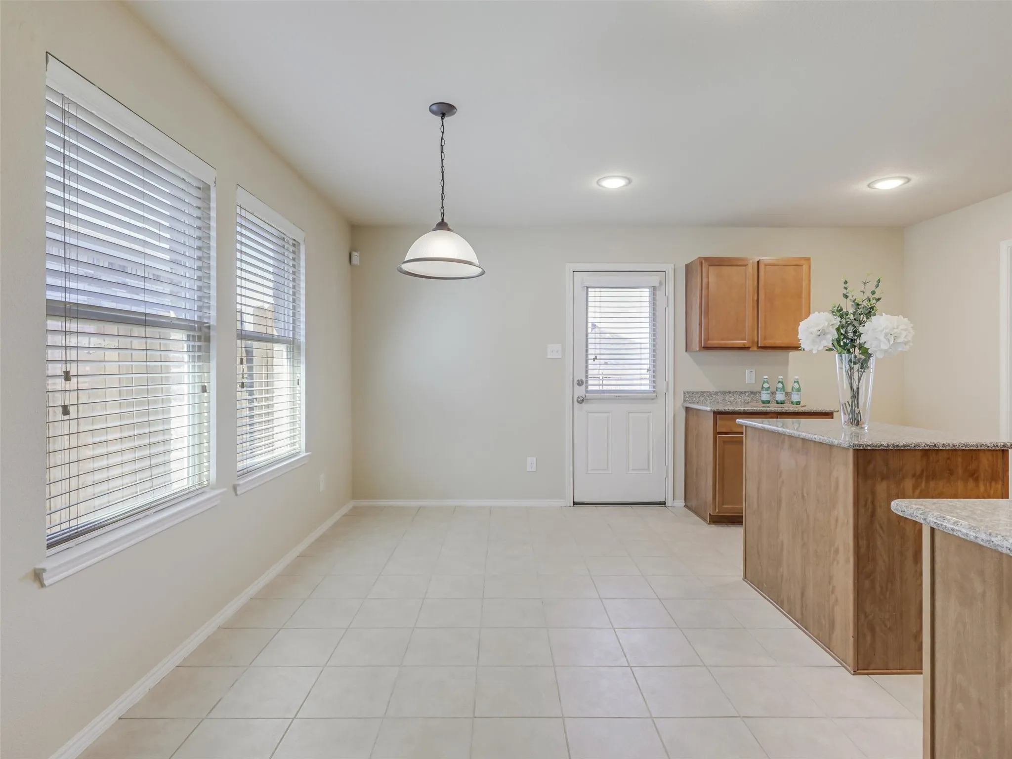 Tile flooring, recessed lighting, pendant lighting, wood-finish cabinetry, and granite-look countertops