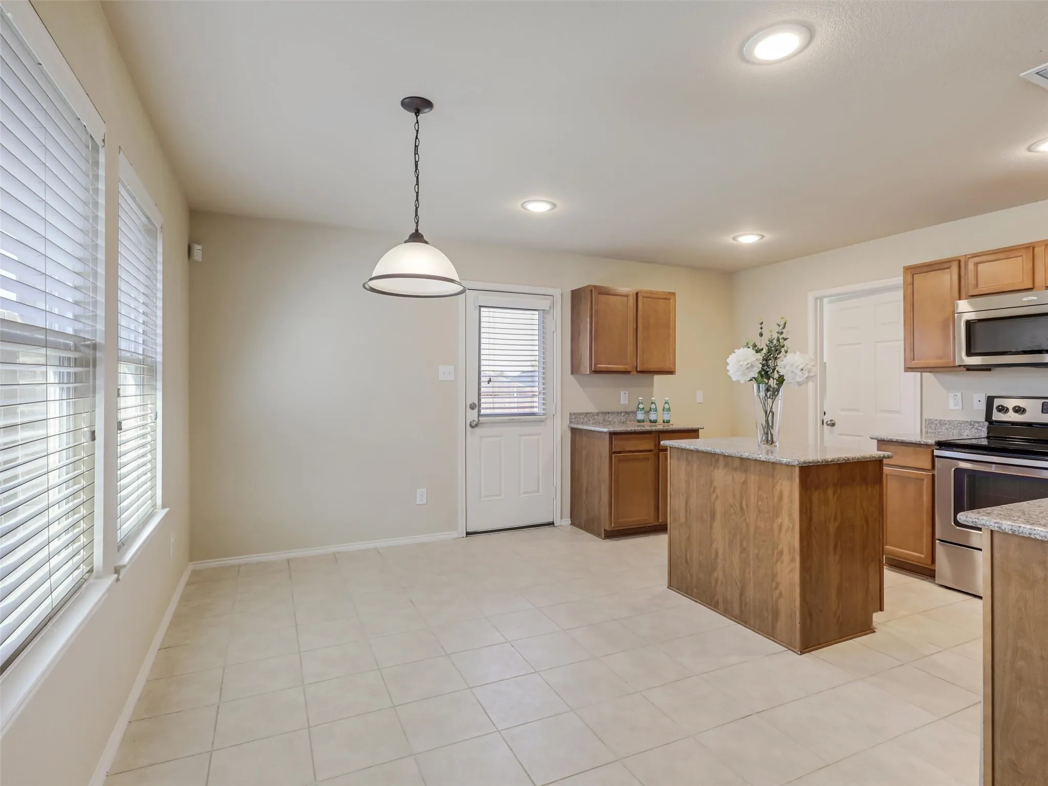 Kitchen featuring a central island, light wood-finish cabinetry, stainless steel appliances, recessed lighting, and tile flooring