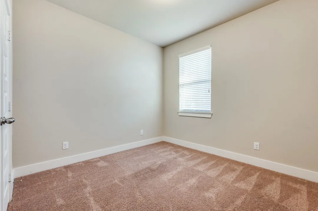 Neutral-toned walls with a single window featuring horizontal blinds