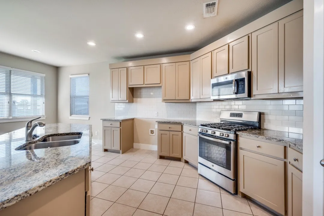 Kitchen featuring granite countertops, tile flooring, stainless steel appliances, recessed lighting, and a subway tile backsplash