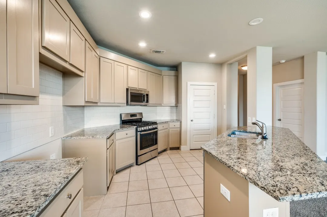 Kitchen featuring granite countertops, stainless steel appliances, tile flooring, subway tile backsplash, and recessed lighting