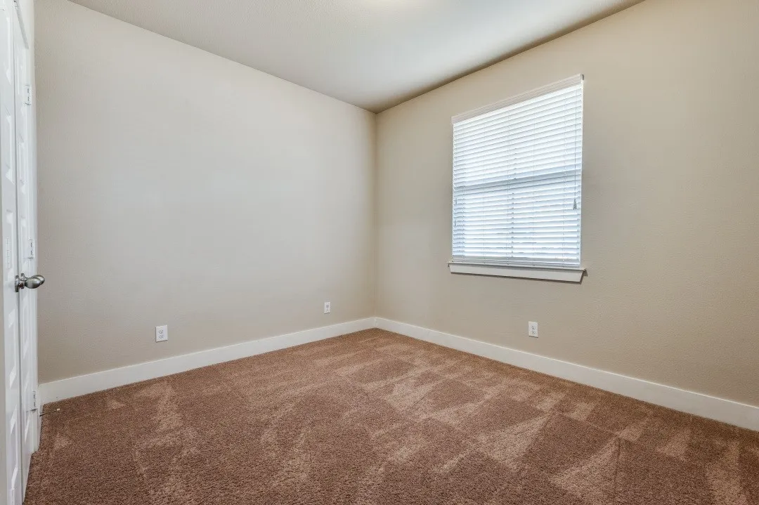 Neutral tone walls with white trim, brown carpet, and a window with blinds
