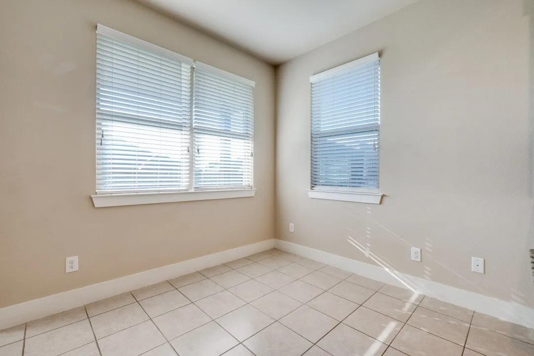 Multiple windows with horizontal blinds, neutral wall paint, and tile flooring