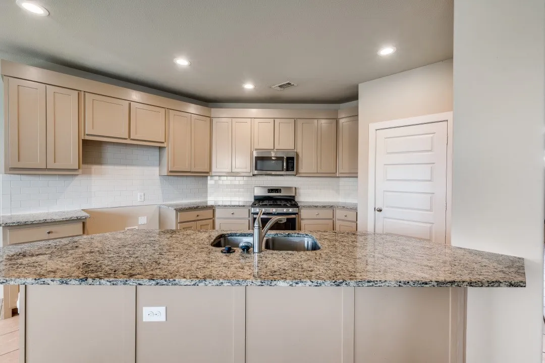 Kitchen featuring an island with an undermount sink, granite countertops, stainless steel appliances, and recessed lighting