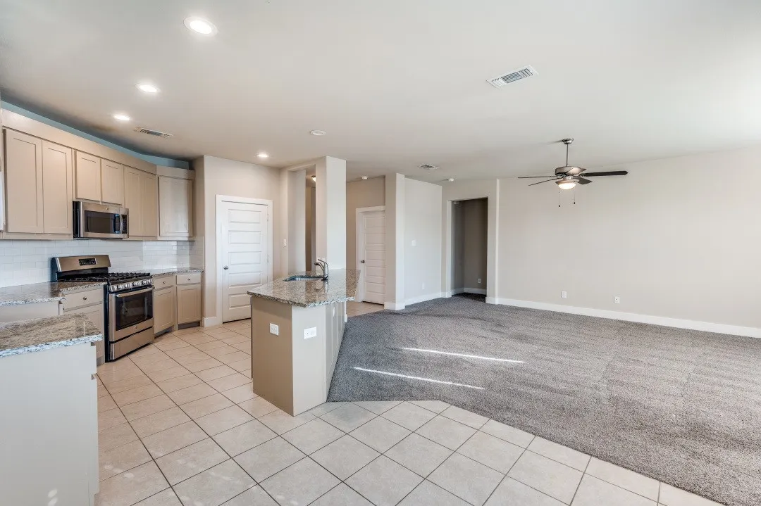 Kitchen featuring stainless steel appliances, light cabinetry, granite countertops, and tile flooring