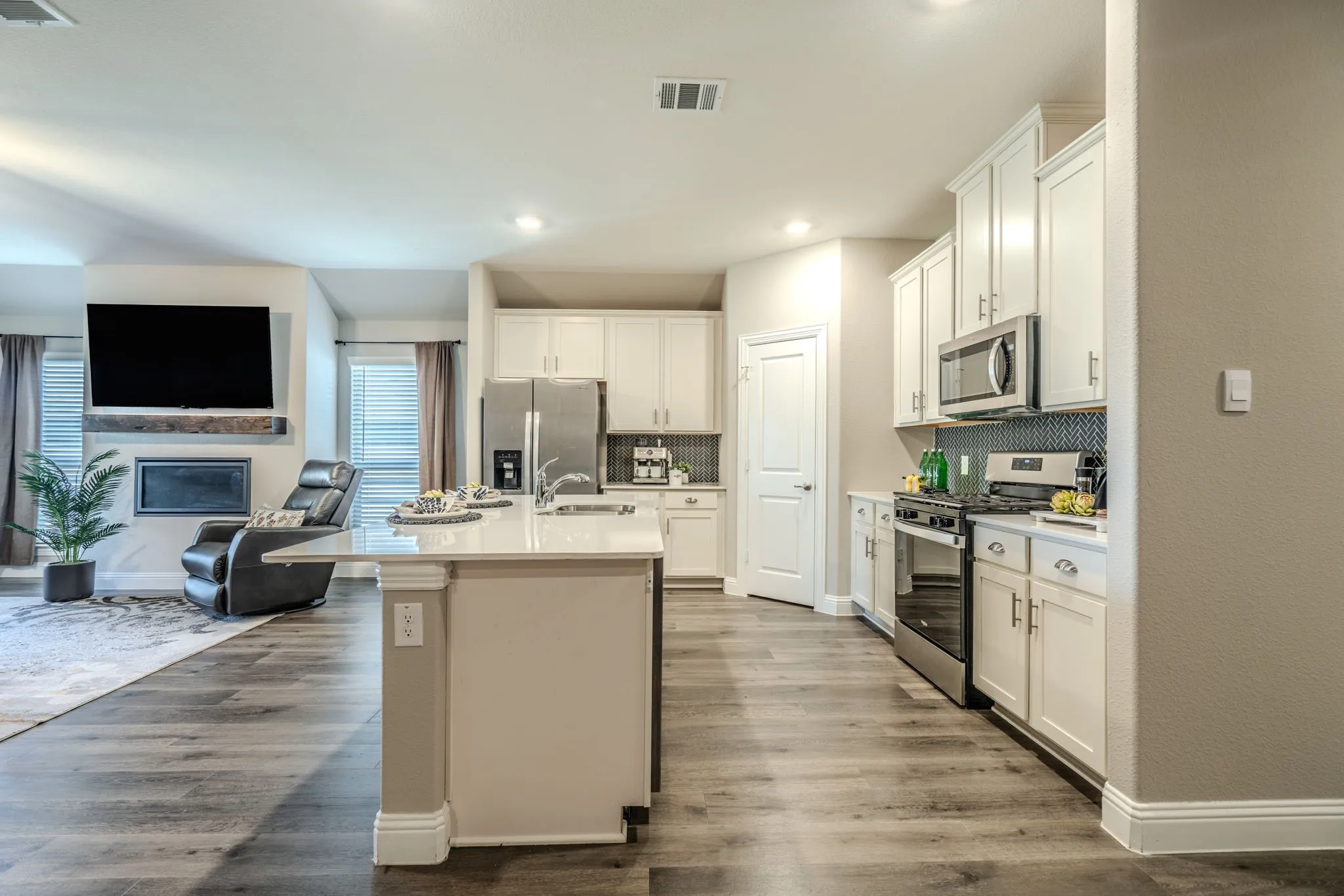 7329 Allium Court, Little Elm, TX 76227 - kitchen -Open-concept kitchen featuring white cabinetry, stainless steel appliances, and a central island with a sink