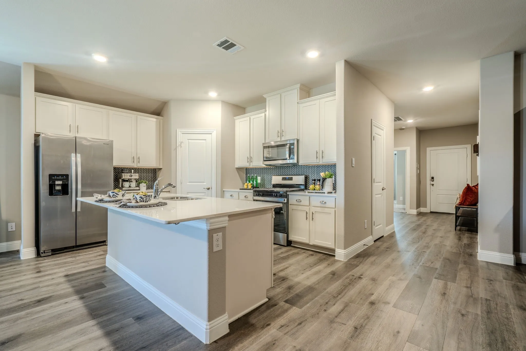 7329 Allium Court, Little Elm, TX 76227 - kitchen - Kitchen featuring white cabinetry, stainless steel appliances, a center island with sink, and wood-finish flooring