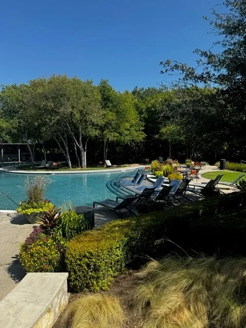 Resort-style pool with integrated steps, surrounding lounge seating, and lush landscaping