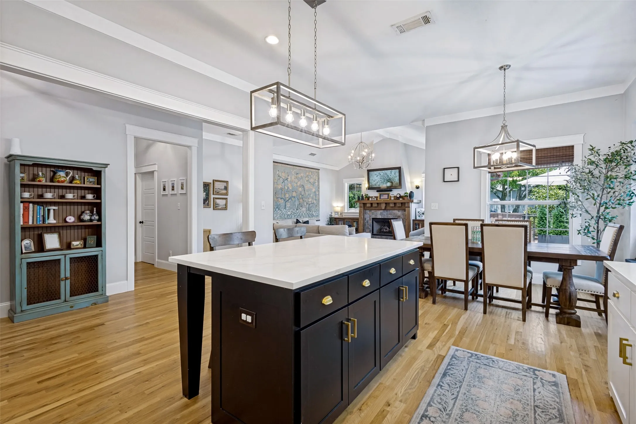 Hardwood flooring throughout, a kitchen island with white countertop, recessed lighting, and a dining area with pendant lighting