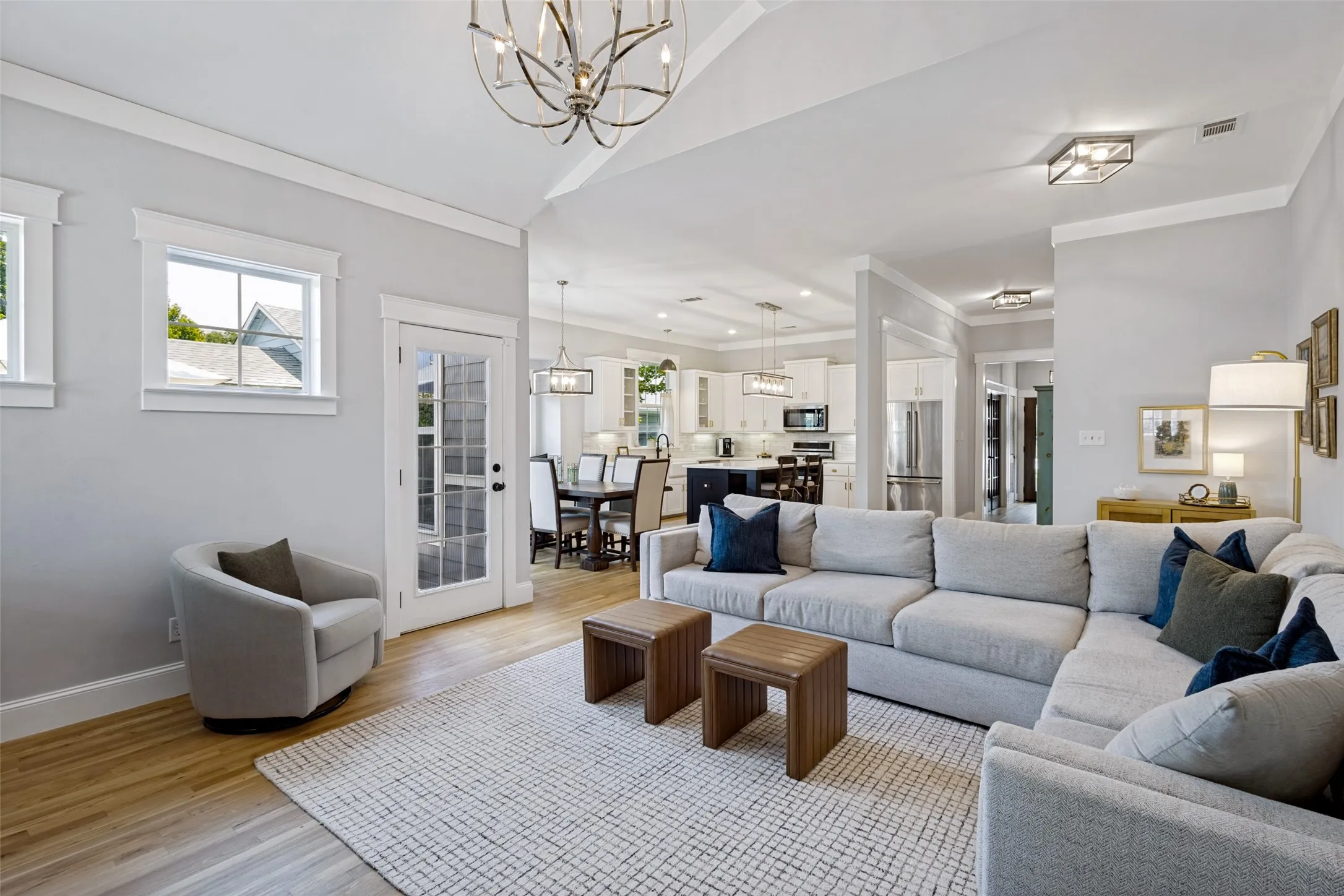 Vaulted ceiling with an ornate chandelier, wood-finish flooring, French door with glass panels, large windows, and recessed lighting