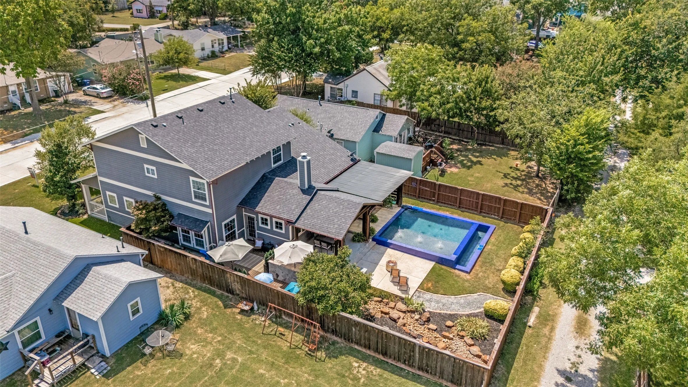 Rear exterior featuring a swimming pool, covered patio, fenced yard, and established landscaping