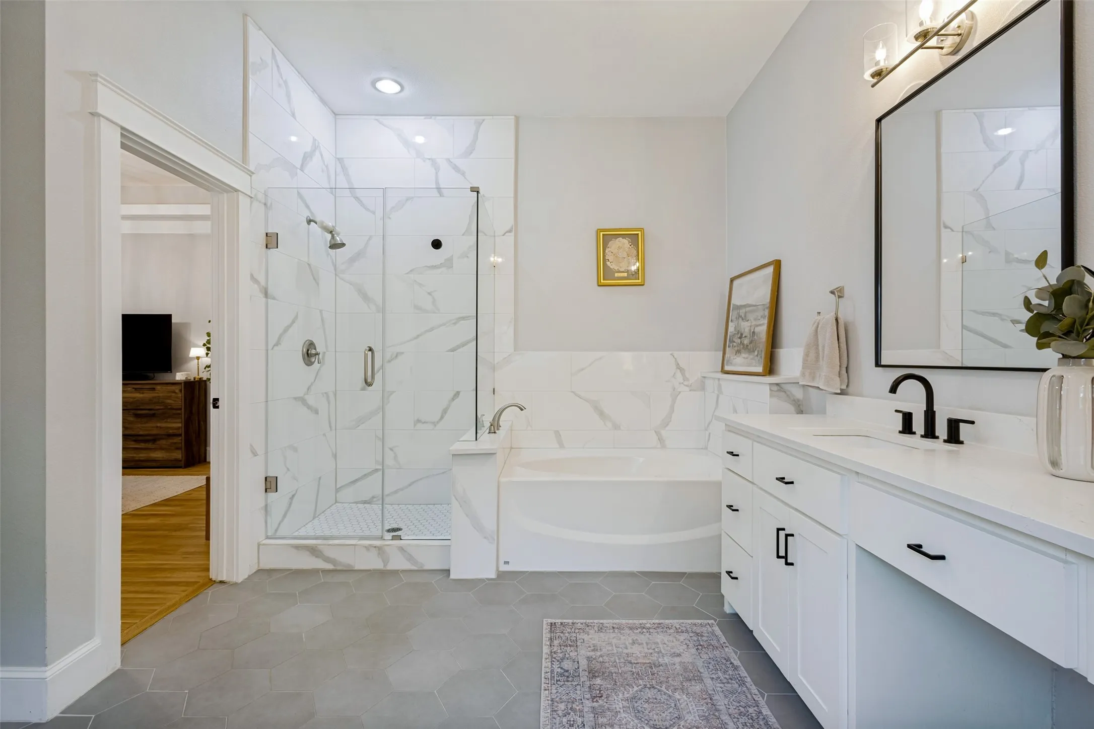 Glass-enclosed shower with subway tile surround, separate soaking tub, and a vanity with dual sinks