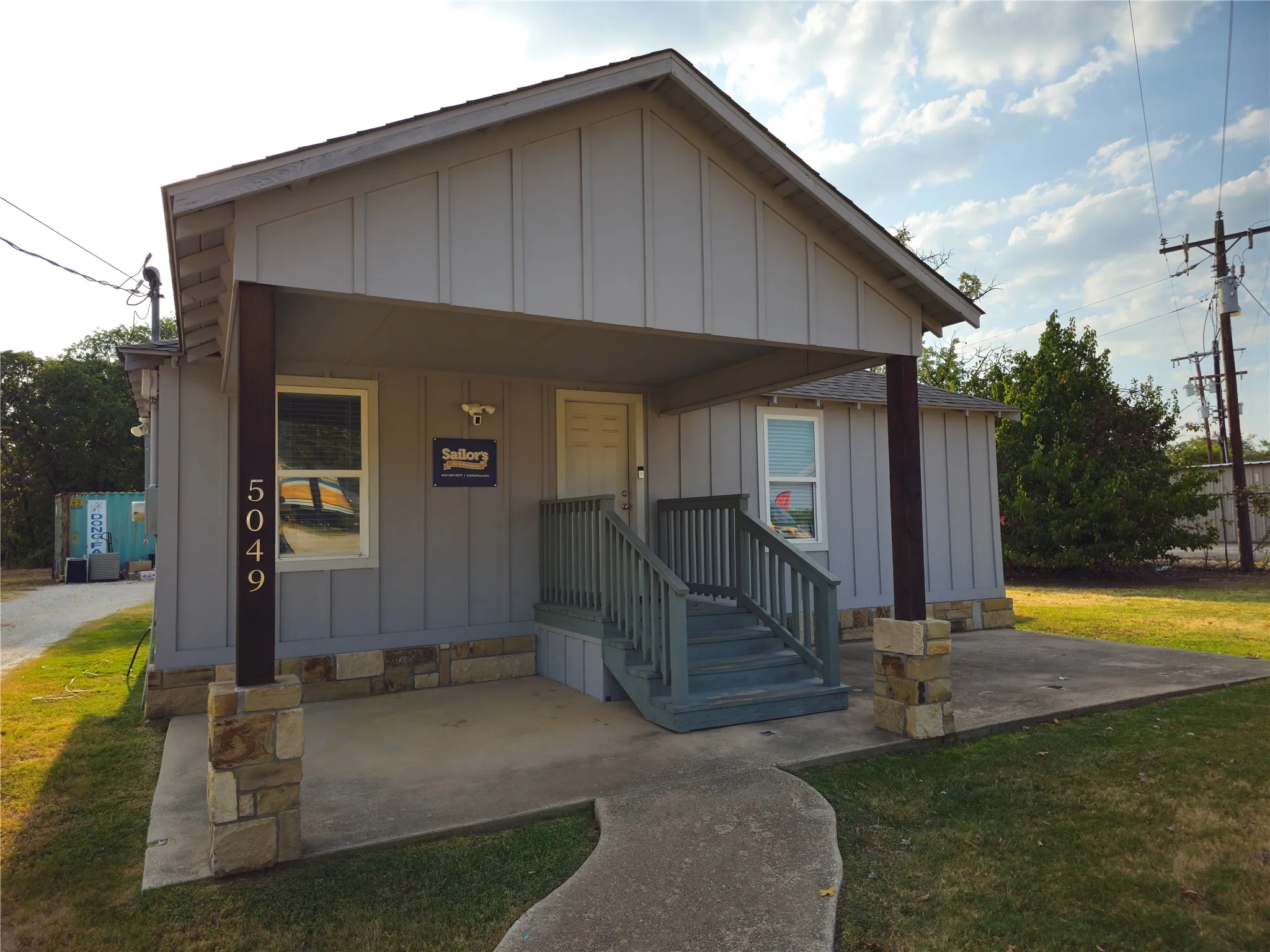 Modern cottage-style office featuring a welcoming front elevation with vertical board-and-batten siding in gray and cream tones