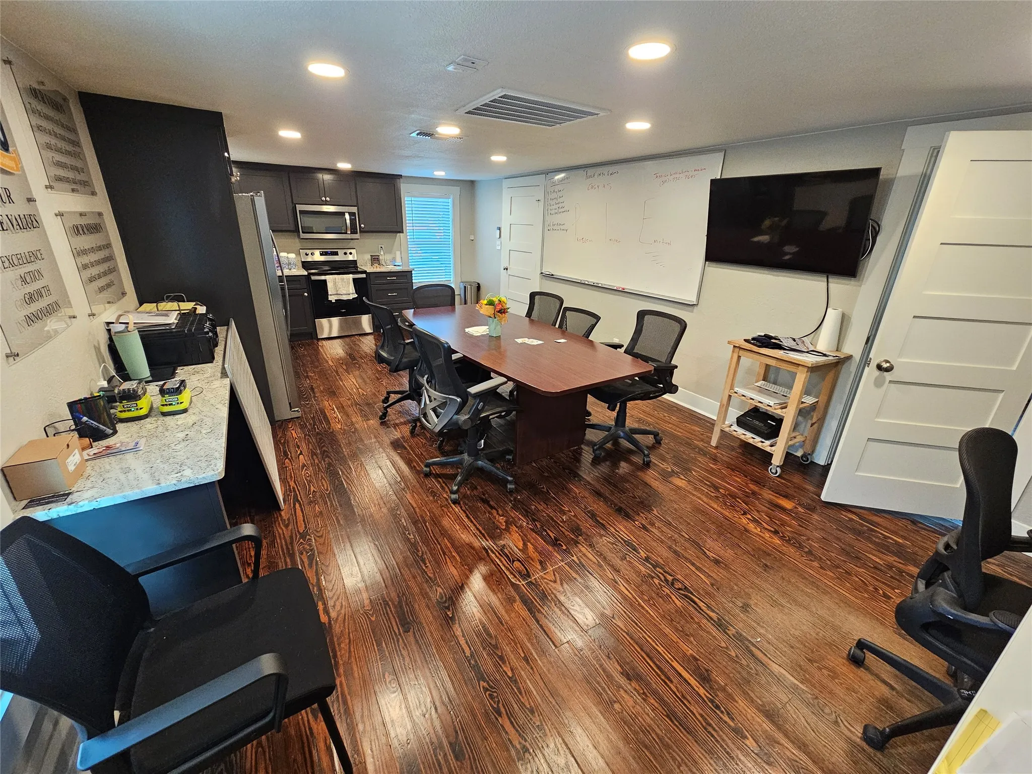 Open-concept space featuring rich wood-finish flooring, recessed lighting, and a functional kitchen area