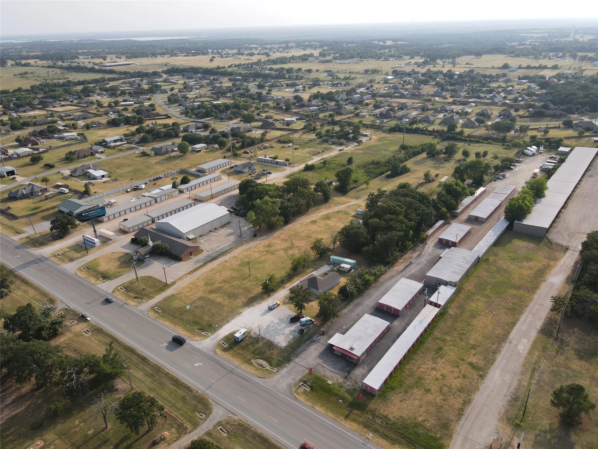 Aerial overview showcasing multiple storage unit buildings, paved access roads, and extensive open land