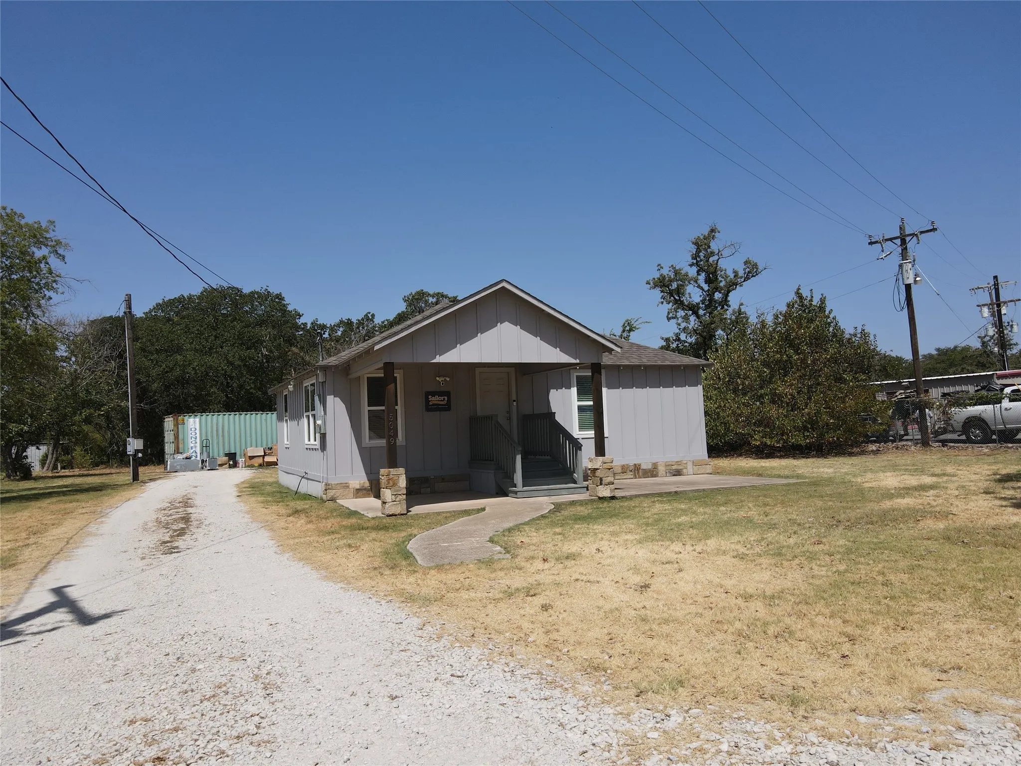 Front exterior featuring a gravel driveway, covered entry porch, and stone-clad porch columns