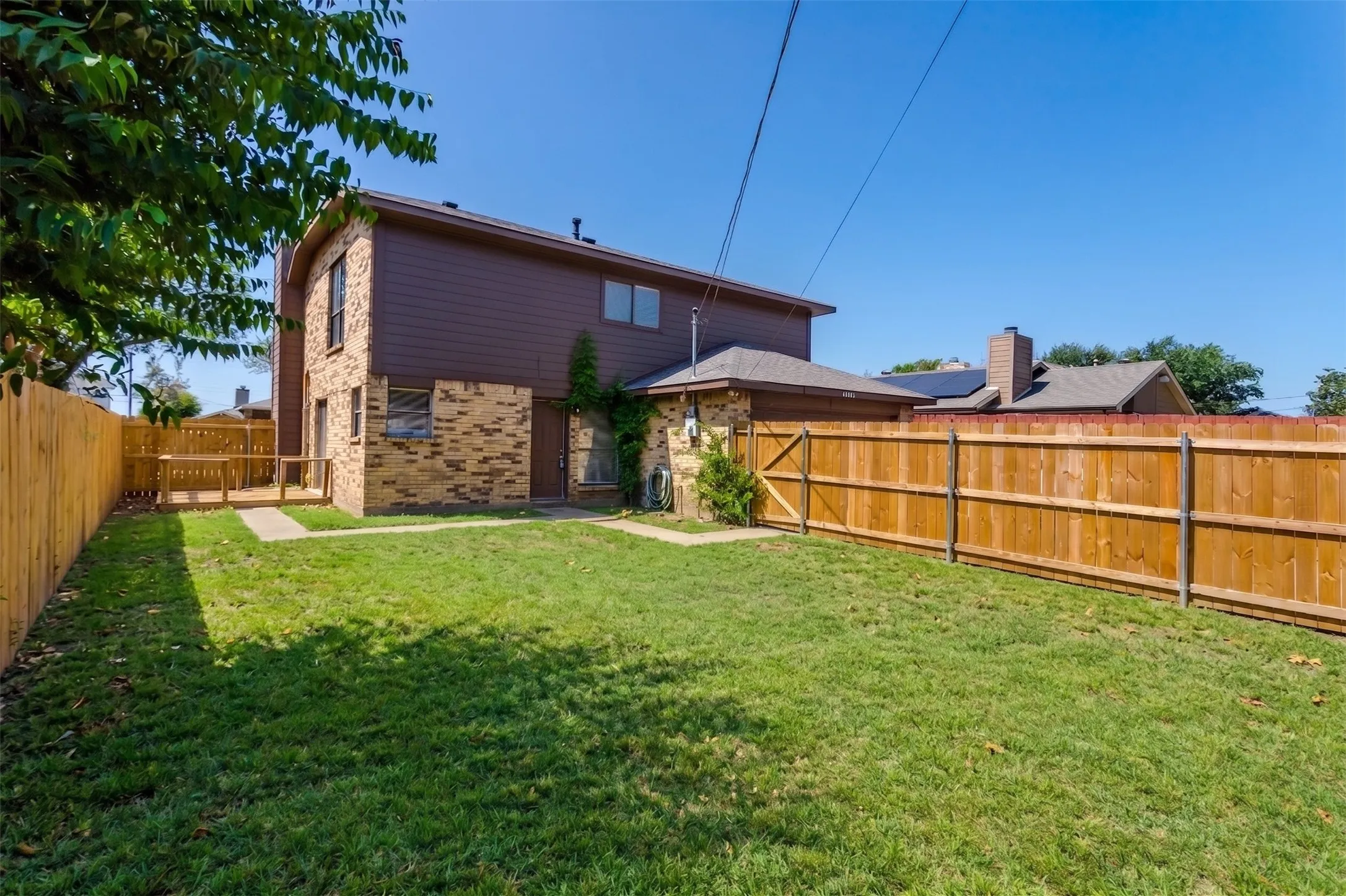 Huge backyard with wooden deck off of sliding doors on side of home