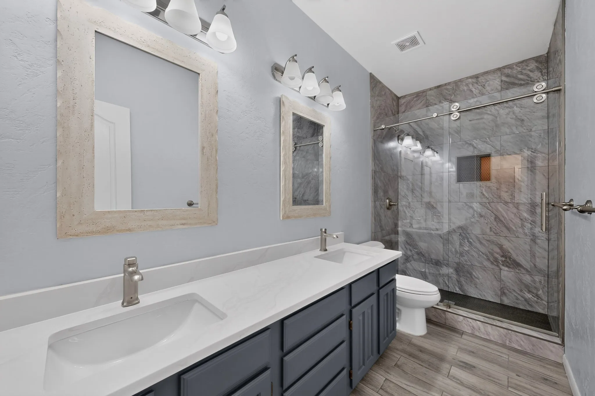 Dual vanity with integrated sinks, brushed nickel faucets, and framed mirrors