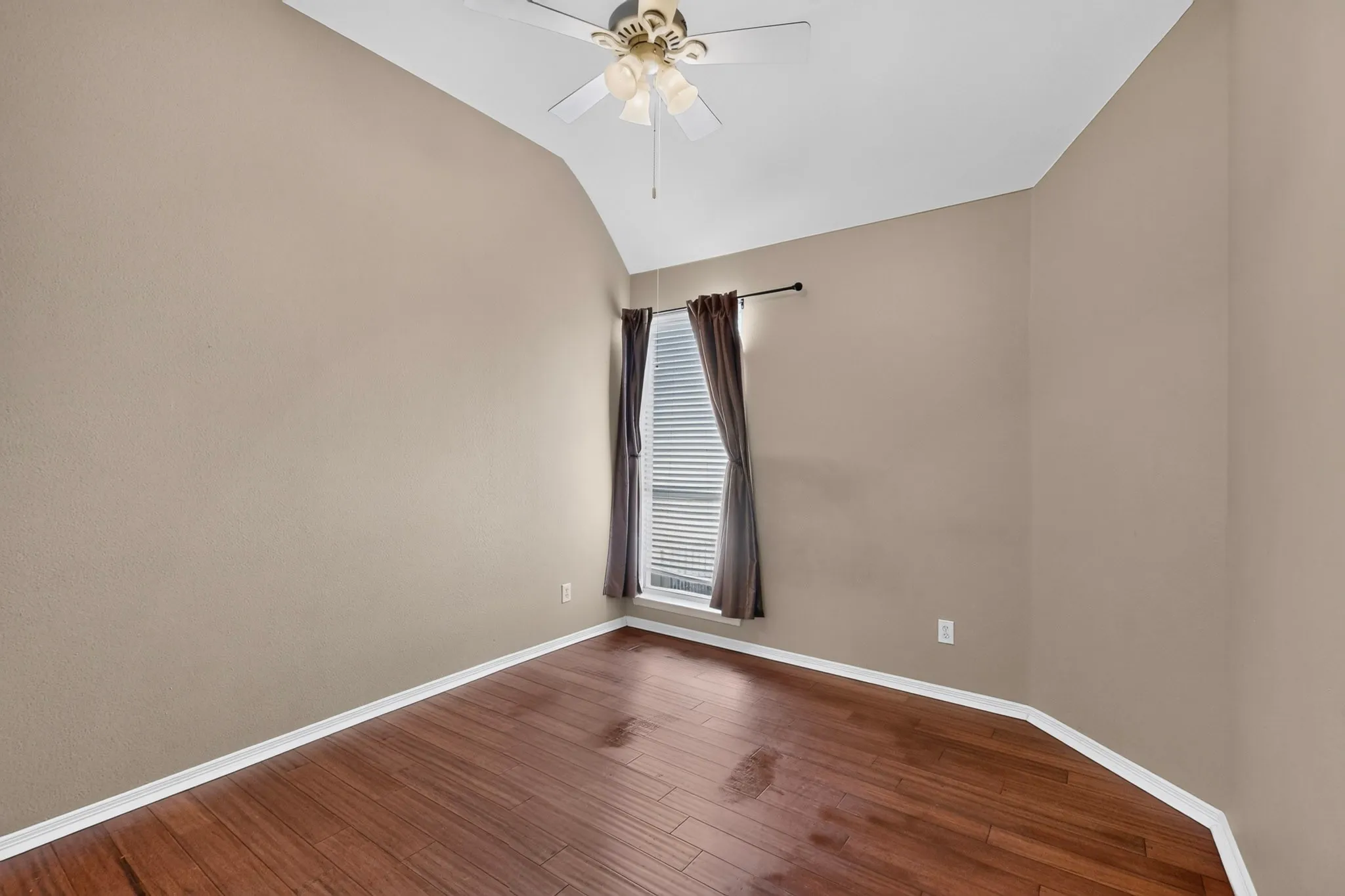 Vaulted ceiling with a ceiling fan, wood-finish flooring, and natural light
