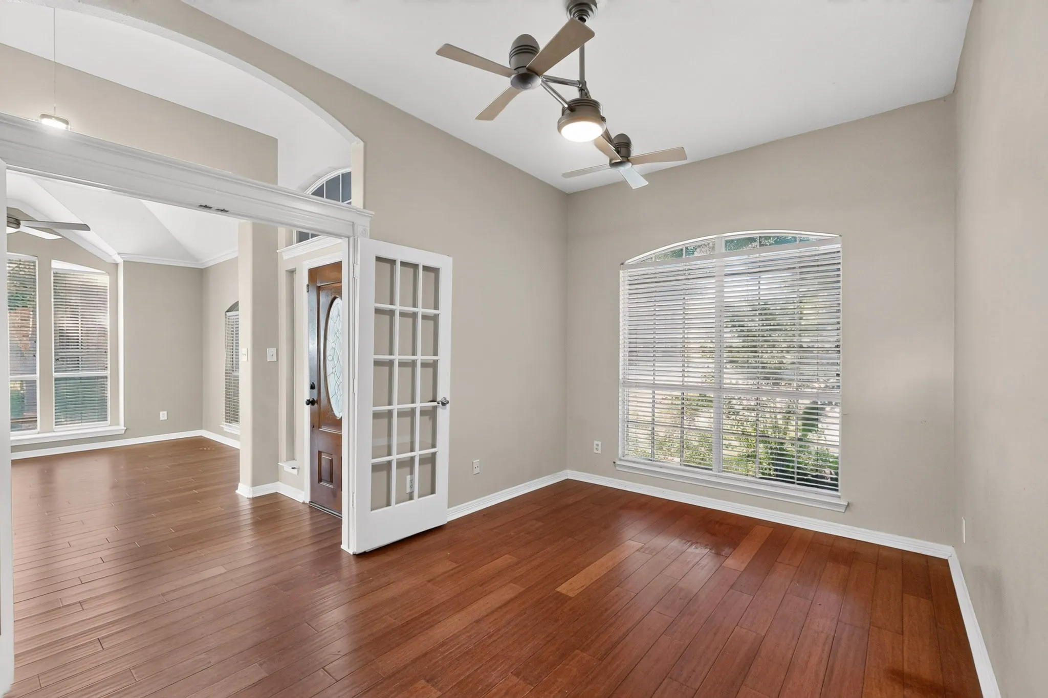 Wood-finish flooring, vaulted ceiling, arched doorways, French doors, and an arched window