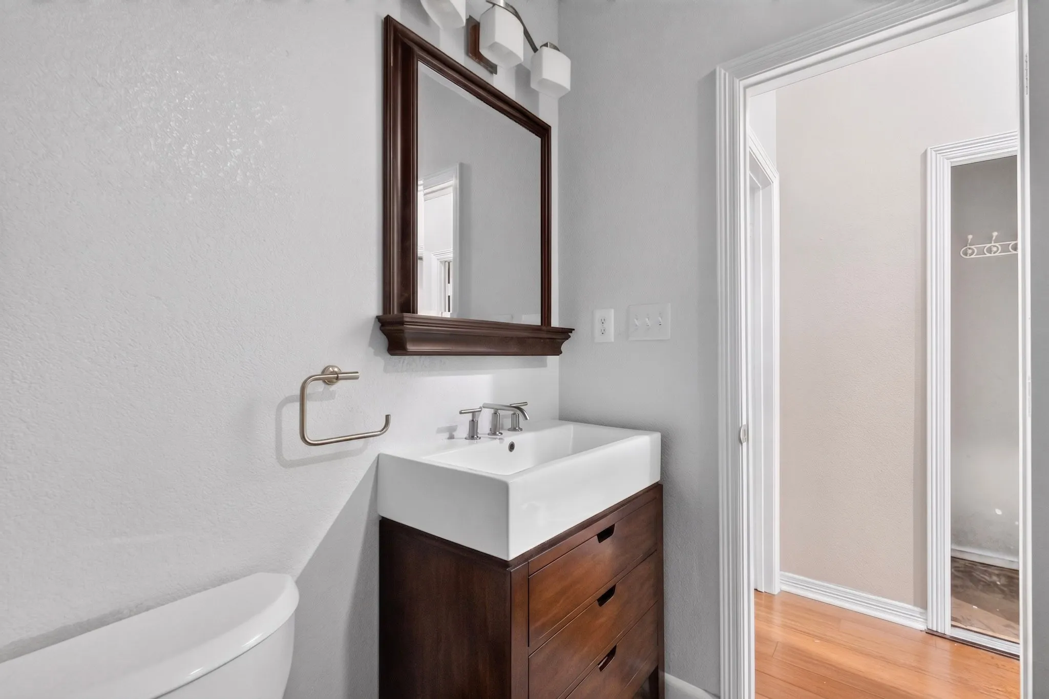 Wood-finish vanity with drawer storage, white rectangular vessel sink, and silver-tone fixtures