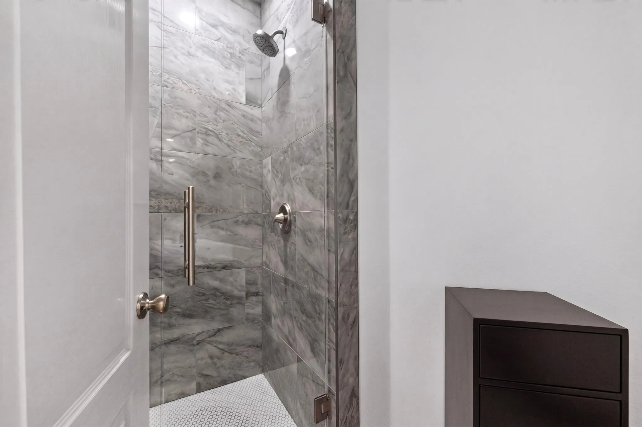 Tiled walk-in shower with a glass enclosure, rainfall showerhead, and circular floor tile