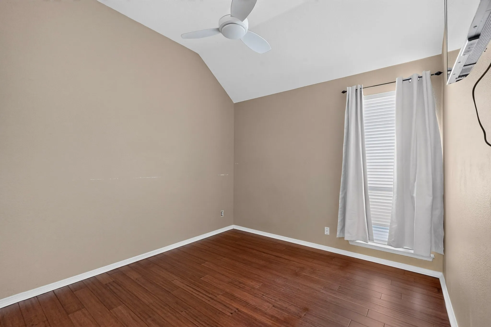 Vaulted ceiling with a ceiling fan, window with blinds, and wood-finish flooring
