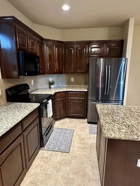 Kitchen featuring recessed lighting, tasteful backsplash, dark brown cabinetry, black appliances, and light tile patterned floors