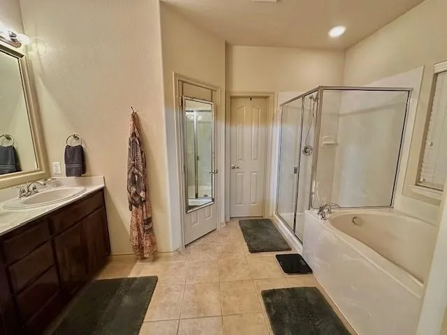 Full bath with tile patterned flooring, vanity, a stall shower, and a garden tub
