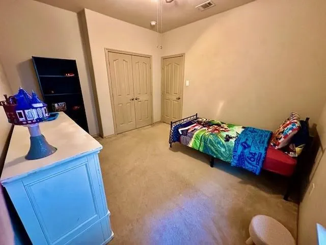 Bedroom featuring a closet, light colored carpet, and visible vents