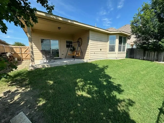 Rear view of property featuring a fenced backyard, a lawn, and a patio
