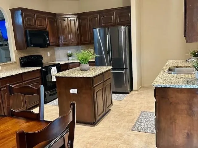 Kitchen with a sink, decorative backsplash, black appliances, and dark brown cabinets