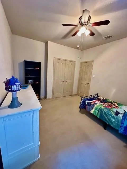 Bedroom with a ceiling fan, a closet, light colored carpet, and visible vents