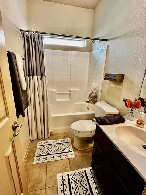 Bathroom with shower / tub combo with curtain, toilet, tile patterned flooring, and vanity