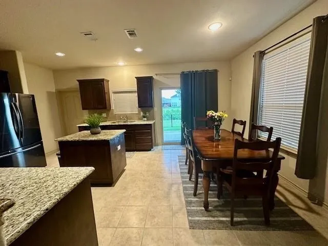 Kitchen with visible vents, a kitchen island, dark brown cabinetry, a sink, and freestanding refrigerator
