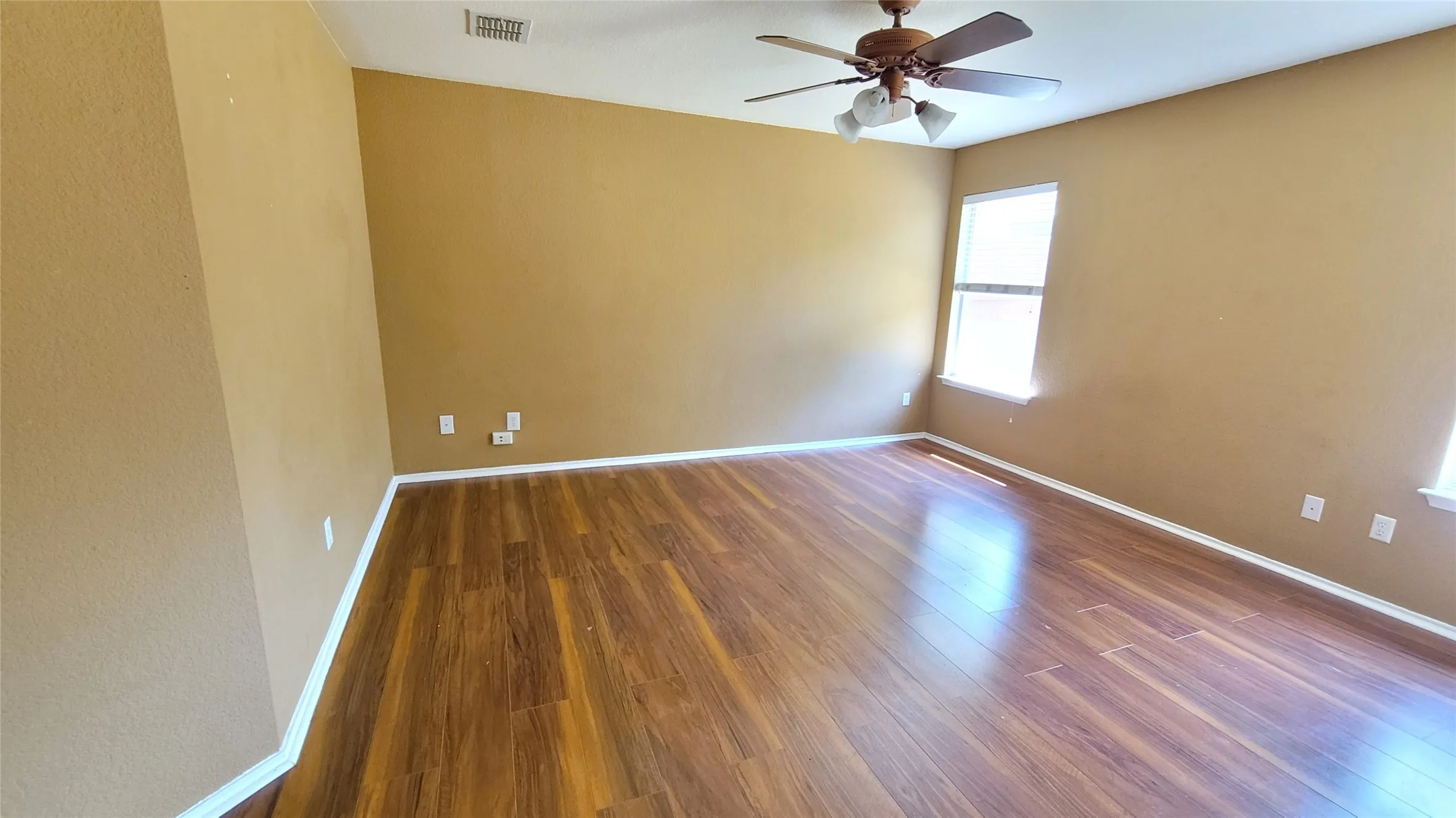 Wood-finish flooring, ceiling fan with integrated lighting, and multiple windows