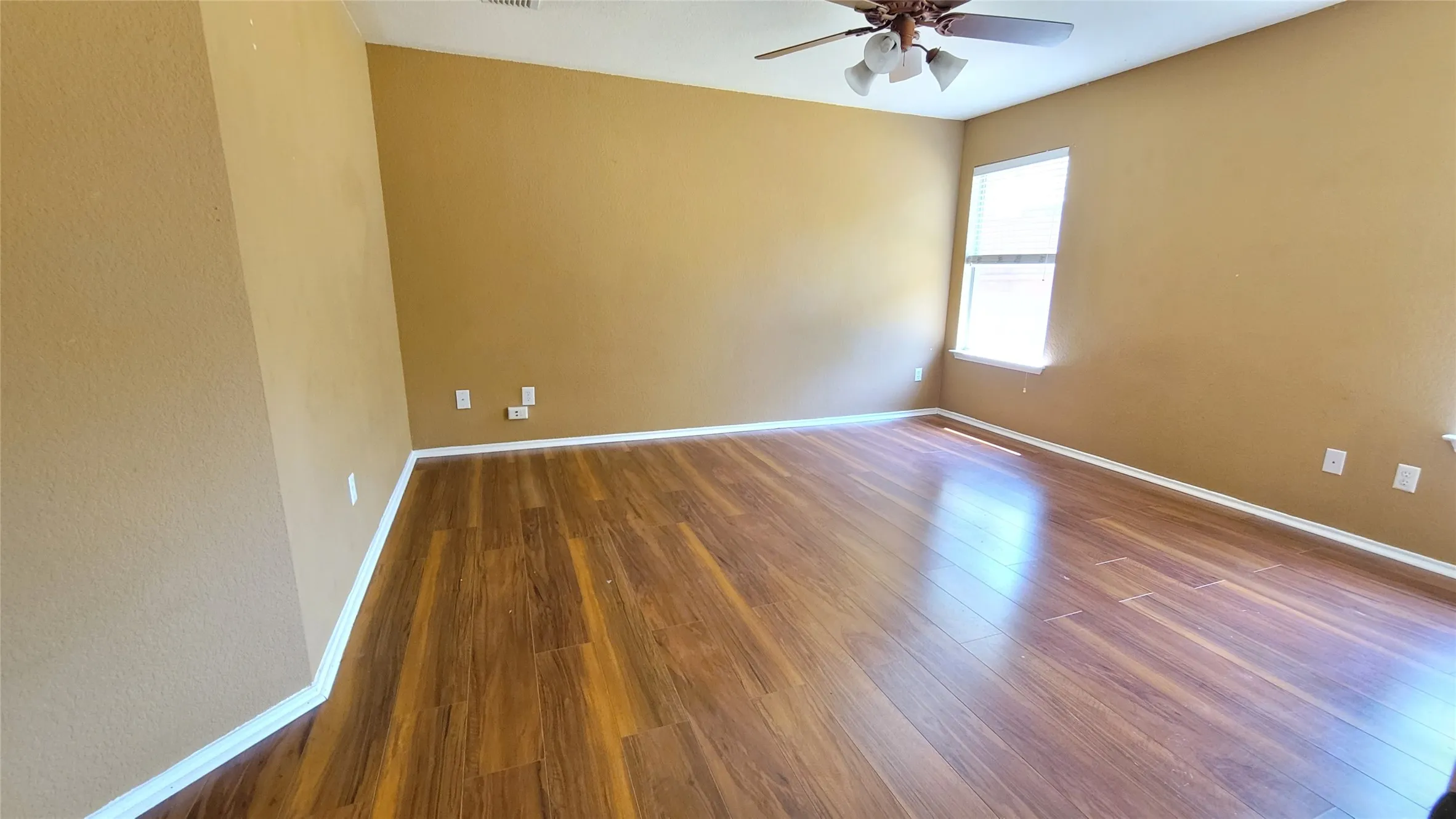 Recessed ceiling, wood-finish flooring, ceiling fan with integrated lighting, and window