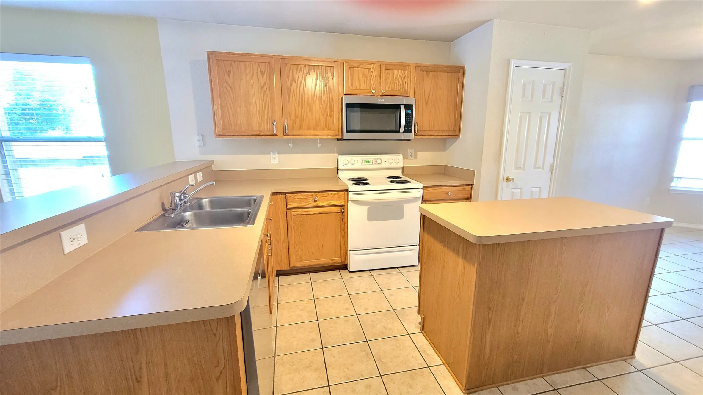 Kitchen featuring wood-finish cabinetry, a double basin sink, and a center island