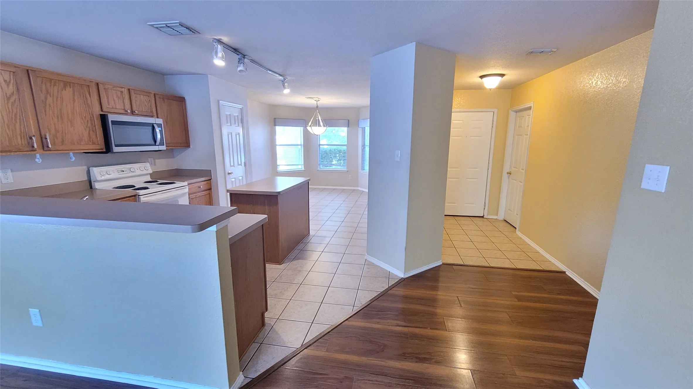 Kitchen featuring wood-finish cabinetry, stainless steel microwave, and built-in electric range