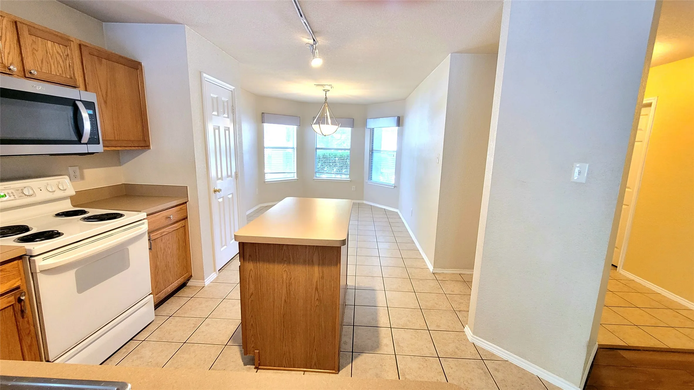Kitchen featuring a built-in microwave, wood-finish cabinetry, a central island, and tile flooring