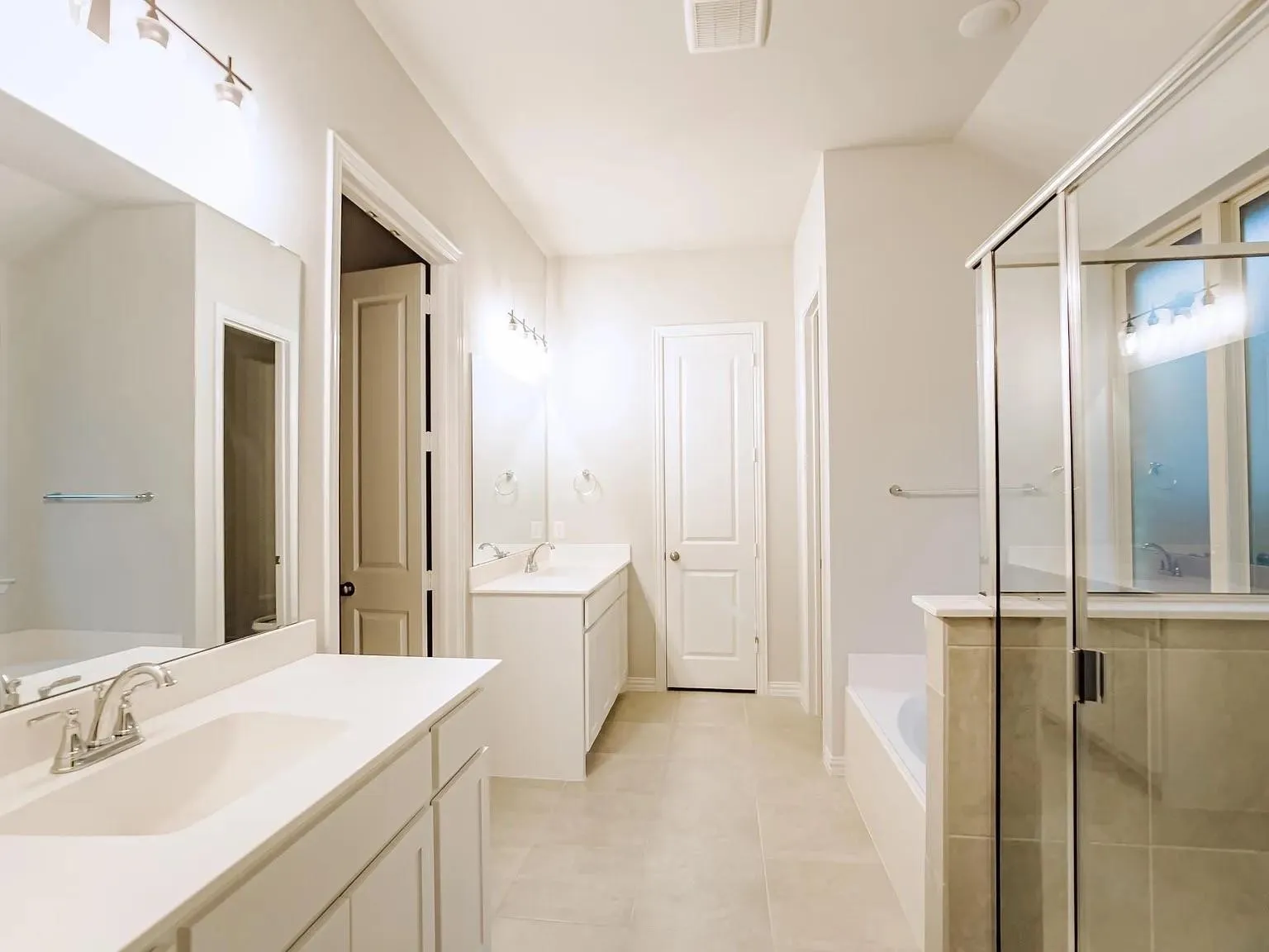 Dual vanities with integrated sinks, tiled flooring, built-in soaking tub, and a glass-enclosed shower