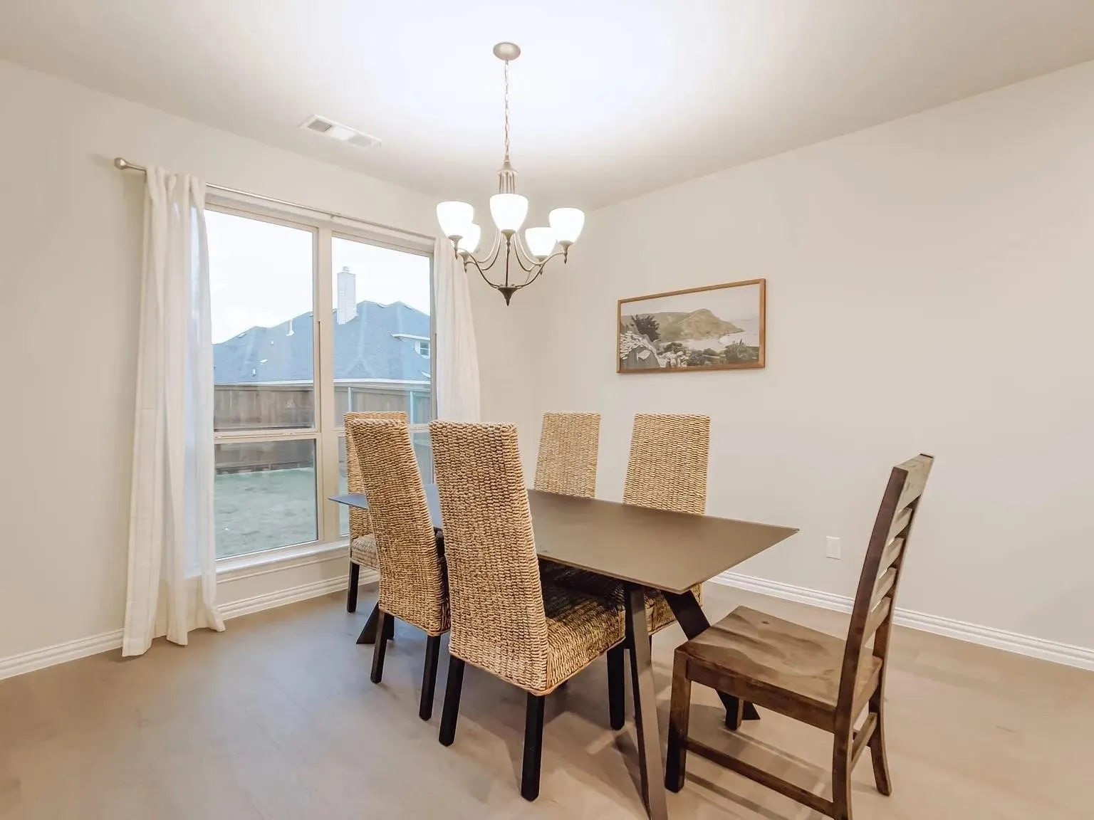 Wood-finish flooring, large window with backyard exposure, perimeter base molding, and a built-in ceiling light fixture