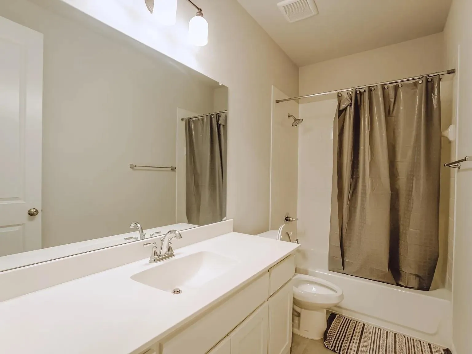 Built-in vanity with an integrated sink, polished chrome faucet, and expansive wall-mounted mirror