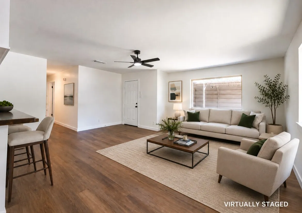 Spacious living area featuring wood-finish flooring, white walls, and a contemporary ceiling fan