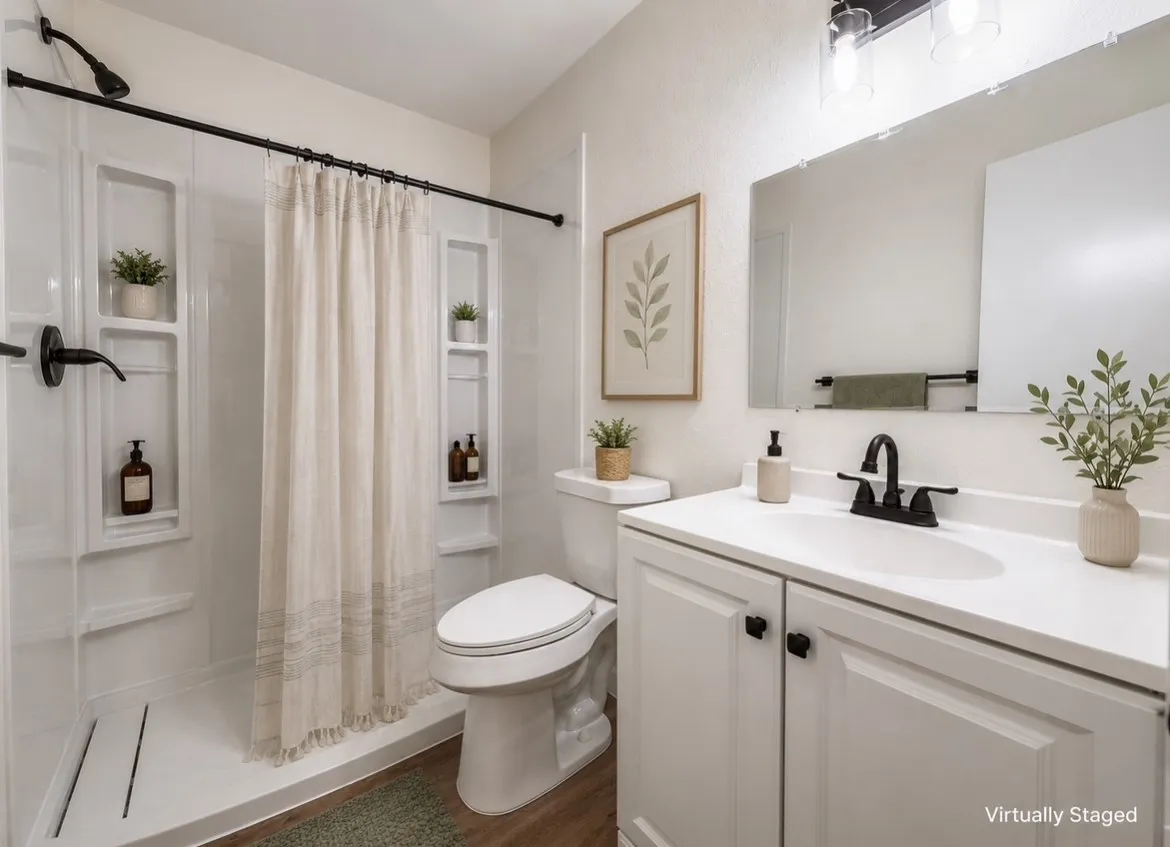 Bathroom featuring a white vanity with integrated sink, matte black fixtures, an expansive wall mirror, a commode, and a shower with built-in shelving