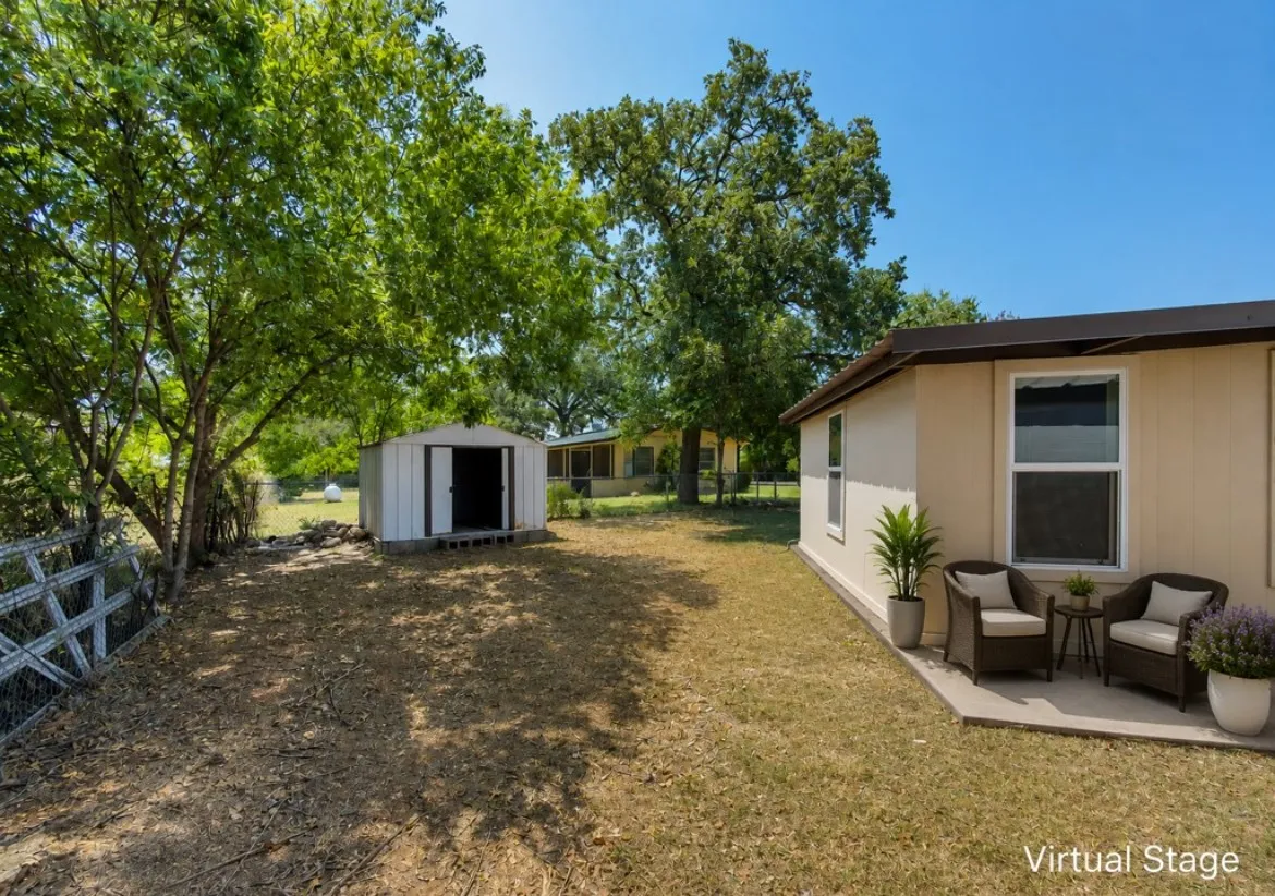 Expansive outdoor area featuring a storage shed, mature trees, and a concrete patio